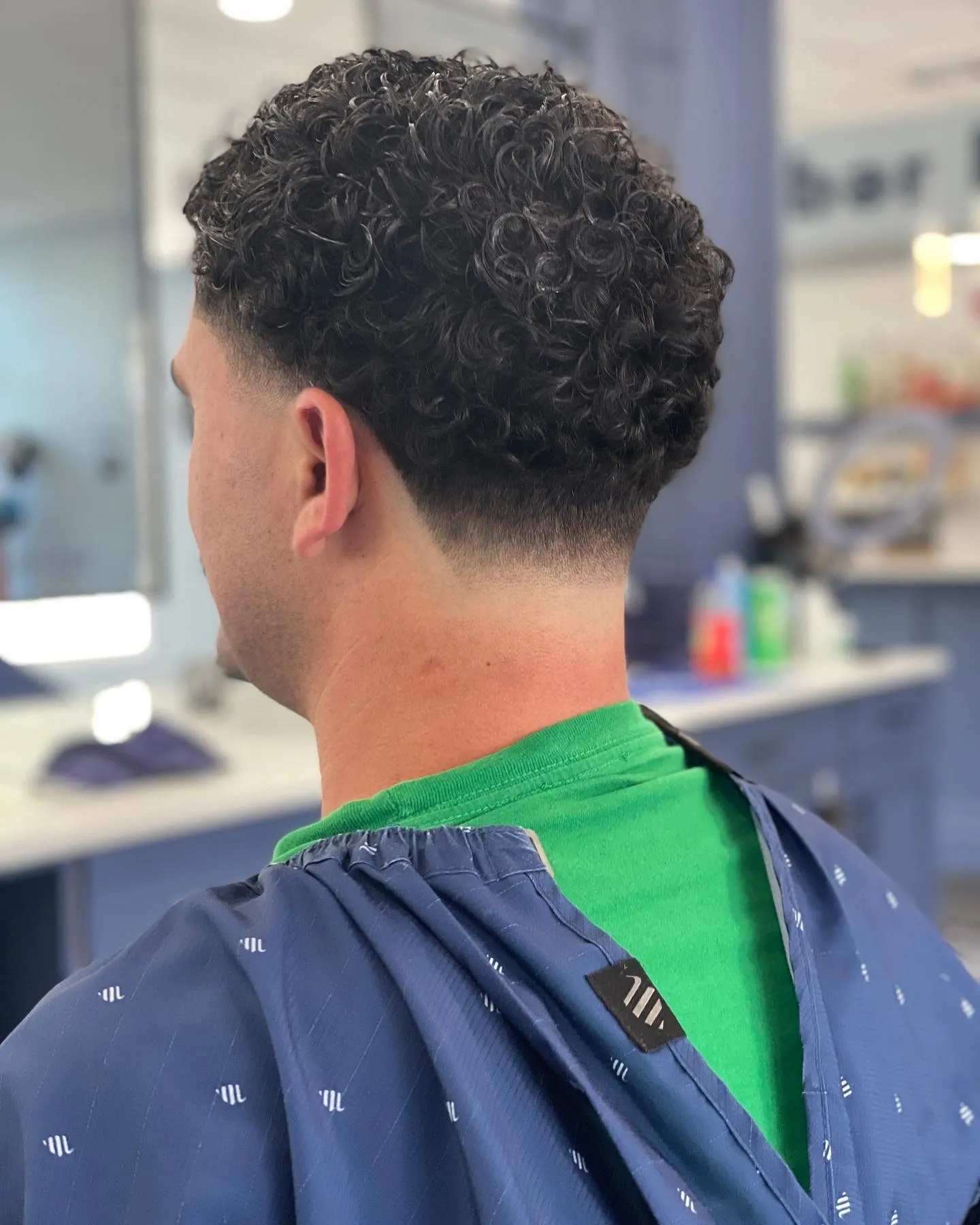 A man with curly hair is getting his haircut.